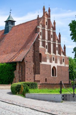 Malbork, Poland - June 25, 2020: Gothic St. Lawrence Church next to 13th century Malbork Castle, medieval Teutonic fortress on the River Nogat. It is the largest castle in the world, UNESCO World Heritage Site