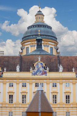 Melk, Avusturya - 24 Şubat 2023: Melk Abbey şehrin yukarısındaki tepede, Prelate 'nin avlusunda bir bina ön cephesi. Uzakta Melk Koleji Kilisesi Kubbesi