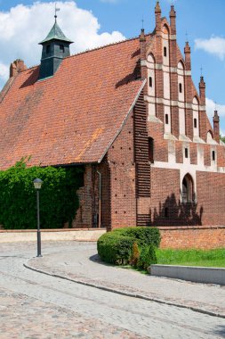 Malbork, Poland - June 25, 2020: Gothic St. Lawrence Church next to 13th century Malbork Castle, medieval Teutonic fortress on the River Nogat. It is the largest castle in the world, UNESCO World Heritage Site