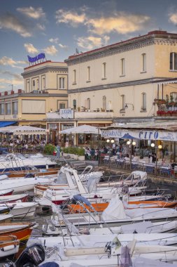 Naples, Italy - June 27, 2021: View of harbor by Passage Castel dell'Ovo with moored boats and people hanging out in seafront restaurants clipart