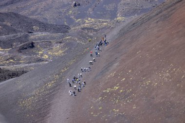 Etna Dağı, Sicilya, İtalya - 27 Nisan 2023: Güneşli bir günde Etna Yanardağı 'ndaki Silvestri Krateri' nin yamaçlarında yürüyen insanlar. Taşlar, katı lav, kurumuş bitki örtüsü.