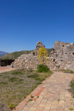 Mola Kalesi 'nin kalıntıları, eski Norman istihkamlarının bir parçası küçük bir vilamın üzerindeki tepenin üstünde sarı rezene çiçeği, Castelmola; Sicilya; İtalya. Küçük köy son zamanlarda popüler bir turizm beldesi.
