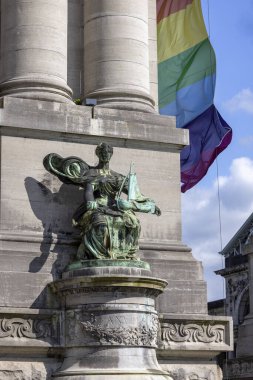 Brüksel, Belçika - 16 Mayıs 2023: Cinquantenaire Park 'taki Cinquantenaire Kemeri' nin tabanındaki heykellerden biri. Gökkuşağı bayrağı (LGBT) binada dalgalanıyor