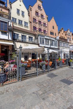 Gdansk, Polonya - 2 Haziran 2023: Balıkçı Sahili 'ndeki renkli tarihi konutların önündeki açık hava restoranları, Motlawa Nehri üzerinde turist gemileri ve Kuğu Kulesi limanının yanındaki bulvarlar