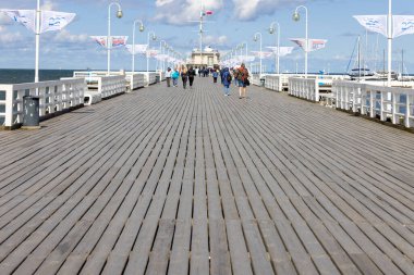 Sopot, Polonya - 2 Haziran 2023: Güneşli bir günde Baltık Denizi 'ndeki Gdansk Körfezi' ndeki ahşap Sopot iskelesinde yürüyen insanlar. Avrupa 'nın en uzun tahta rıhtımıdır ve 511,5 metre uzunluğundadır.