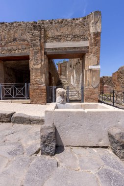 Pompeii, Napoli, İtalya - 26 Haziran 2021: M.S. 79 'da Napoli yakınlarında Vesuvius volkanının patlaması sonucu yıkılan antik bir şehrin kalıntıları. Sokaklardan birinde kullanılacak çeşme