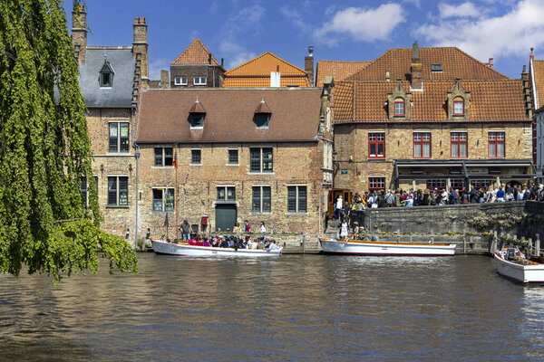 Bruges, Belgium - May 19, 2023: Tourists waiting in port at Rosary Quay for Boat trip for a water channel cruise