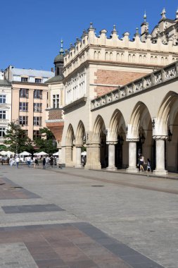 Krakow, Polonya - 6 Eylül 2023: Rönesans Ortaçağ Kuaför Salonu (Sukiennice) Eski Şehir 'in ana meydanında yer almaktadır. Binanın önünde şemsiyeli açık hava restoranı