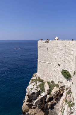 Dubrovnik, Hırvatistan - 27 Haziran 2023: Adriyatik Denizi 'ndeki ortaçağ kentini çevreleyen kulelerden birine sahip Şehir Duvarları manzarası. Tarihi merkezi olan Eski Şehir Dalmaçya 'nın incisi olarak bilinir.