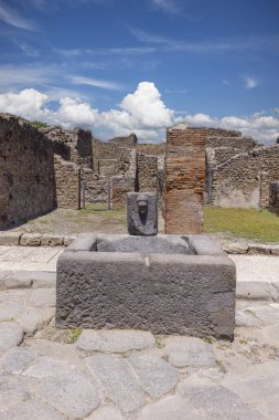 Pompeii, Napoli, İtalya - 26 Haziran 2021: M.S. 79 'da Napoli yakınlarında Vesuvius volkanının patlaması sonucu yıkılan antik bir şehrin kalıntıları. Çeşmeli şehir sokaklarından birinin manzarası