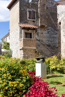Porec, Croatia, Istria - September 25, 2023: The Romanesque House, medieval 13th century building located in Marafor Square. Statue The shape of space in garden, one of Porec Sculp Tours clipart