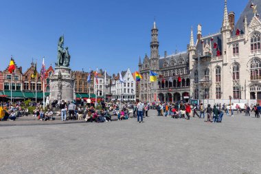 Bruges, Belgium - May 19, 2023: Jan Breydel and Pieter de Coninck Monument on the Market Square (Grote Markt). Colorful traditional tenement houses in the distance clipart