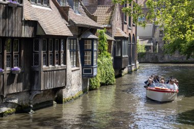 Bruges, Belçika - 19 Mayıs 2023: Beguinage Houses (Begijnhof) yakınlarındaki su kanallarında tekne gezisi sırasında turistler)