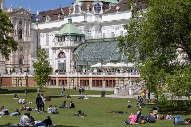 Viyana, Avusturya - 26 Nisan 2024: Güneşli bir günde Hofburg Sarayı ve Kelebek Evi 'nin (Schmetterlinghaus) önündeki Castle Gardens (Burggarten) bahçesinde uzanan insanlar)