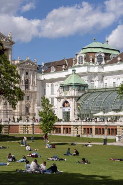 Viyana, Avusturya - 26 Nisan 2024: Güneşli bir günde Hofburg Sarayı ve Kelebek Evi 'nin (Schmetterlinghaus) önündeki Palace Gardens (Burggarten) bahçesinde uzanan insanlar)