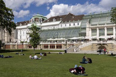 Viyana, Avusturya - 26 Nisan 2024: Güneşli bir günde Hofburg Sarayı ve Kelebek Evi 'nin (Schmetterlinghaus) önündeki Palace Gardens (Burggarten) bahçesinde uzanan insanlar)