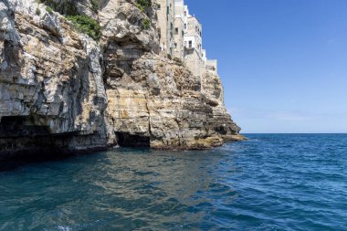 Uçurumlar üzerine inşa edilmiş binalar, resimsel kaya ve mağara denizi manzarası, Polignano a Mare, İtalya, Apulia. Kayalık sahil boyunca bir gezi büyük bir turistik cazibedir.