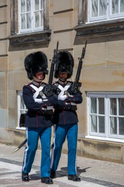 Kopenhag, Danimarka - 22 Haziran 2019: Tarihi üniformalı ve Amalienborg Sarayı önünde kürk şapkalı iki muhafız 