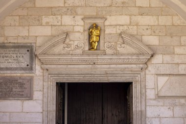 Kotor, Montenegro - June 26, 2023: Facade of Cathedral of Saint Tryphon (Kotor Cathedral), roman catholic medieval church. Entrance door is decorated with a portal with  golden figurine clipart