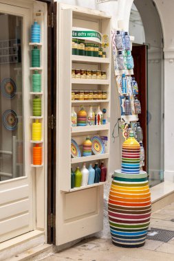 Monopoli, İtalya, Apulia - 21 Mayıs 2024: Seramik vazolar, kupalar, dükkanın önündeki merdivenlerde renkli çizgili saksılar. Akdeniz ülkelerinde sokak dükkanları tipik. 