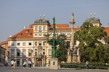 Prag, Çek Cumhuriyeti - 3 Eylül 2024: Prag Kalesi önünde Marian Veba Sütunu (Hradcanske namesti). Uzakta Barok Toskana Sarayı