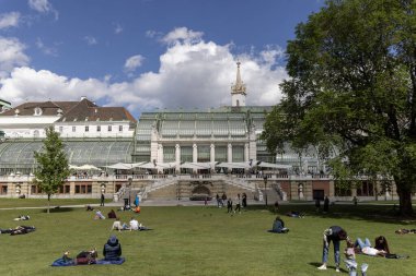 Viyana, Avusturya - 26 Nisan 2024: Güneşli bir günde Hofburg Sarayı ve Kelebek Evi 'nin (Schmetterlinghaus) önündeki Palace Gardens (Burggarten) bahçesinde uzanan insanlar)