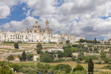 Locorotondo, İtalya, Apulia - 20 Mayıs 2024: Itria Vadisi 'nden şehrin panoramik, pitoresk manzarası. Mavi gökyüzünün arka planında beyaz binalar