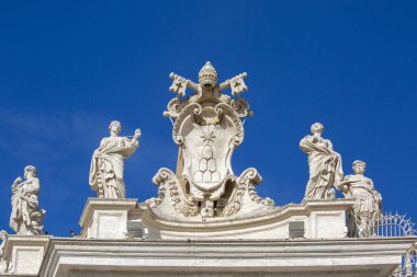 Vatikan, Roma, İtalya - 9 Ekim 2020: Aziz Peter Bazilikası 'nın önündeki Aziz Petrus Meydanı' ndaki sütunların tepesindeki Kutsal Görüş ve Vatikan Şehri 'nin Papa arması