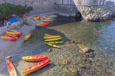 Dubrovnik, Croatia - June 27, 2023: View of marina for colorful kayaks on Kolorina Beach by Adriatic Sea at Old Walls and Bokar tower clipart