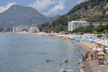 Sutomore, Karadağ - 28 Haziran 2023: Adriyatik Denizi 'nde kumlu sahil, birçok insan su kenarında dinleniyor. Çok popüler bir tatil köyüdür.