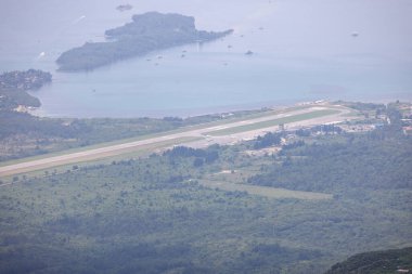 Adriyatik Denizi kıyısındaki Kotor Körfezi, Karadağ 'dan Tivat Havaalanı' nın havadan görünüşü. Ünlü Kotor Serpentine yolu ile ulaşılan dağın tepesindeki gözlem güvertesinden görüntüyü al