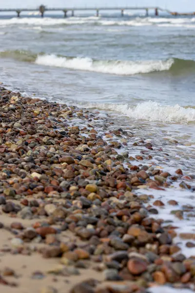 Baltık Denizi 'nin kumlu sahili manzaralı, köpüklü su renkli küçük taşlara akıyor, Wolin Adası, Miedzyzdroje, Polonya