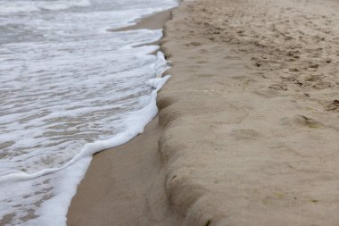 Baltık Denizi 'nin kumlu sahili manzaralı, kuma akan köpüklü su, Miedzyzdroje, Polonya