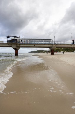 Miedzyzdroje, Polonya - 14 Eylül 2022: Miedzyzdroje iskelesi, sahilden Baltık Denizi 'nin derinliklerine kadar uzanan uzun ahşap iskele, güzel deniz manzarası. Bulutlu gökyüzü ve rüzgarlı hava, sezon dışı olduğu için boş plaj.