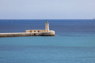 Valletta, Malta - 17 Nisan 2025: Deniz feneri ve St. Elmo Breakwater, Saint Elmo Kalesinden Grand Harbour 'a kadar, Akdeniz' in sakin mavi sularıyla çevrili.
