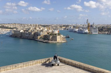 Valletta, Malta - 17 Nisan 2025: Yukarı Barrakka Bahçeleri 'nden Saint Angelo Kalesi' ne, sarı kireçtaşından yapılmış ortaçağ kalesine. Selamlama Bataryasına büyük tarihi top yerleştirildi