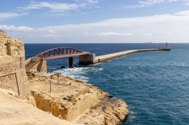 Valletta, Malta - 17 Nisan 2025: St. Elmo Köprüsü ve Saint Elmo Kalesi 'nden Grand Harbour' a kadar uzanan tarihi kırmızı çelik köprü, Akdeniz 'in mavi sularıyla çevrili.