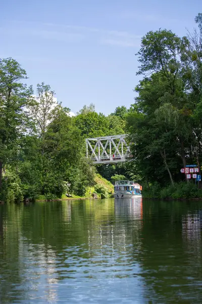 Masuria, Masurian Lake Land, Polonya - 24 Haziran 2020: Masurian Lakes 'deki Nidzkie Gölü manzarası, demiryolu köprüsü altında seyreden turist teknesi