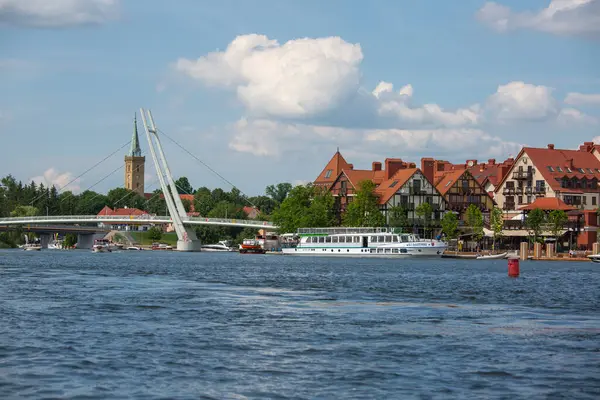 Mikolajki, Masurian Lake Land, Polonya - 24 Haziran 2020: Asma köprünün Mikolajskie Gölü manzarası, yat ve tekneler için yat limanı. Kutsal Üçlü Kilisesi