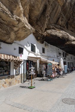 Setenil de las Bodegas, İspanya, Endülüs - 2 Nisan 2025: Uçurumun üzerindeki eşsiz beyaz köy kayalara inşa edildi. Calle Cuevas del Sol caddesindeki dükkan ve restoranlar.