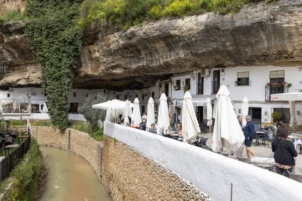 Setenil de las Bodegas, İspanya, Endülüs - 2 Nisan 2025: Uçurumun üzerindeki eşsiz beyaz köy kayalara inşa edildi. Calle Cuevas del Sol caddesindeki dükkan ve restoranlar.