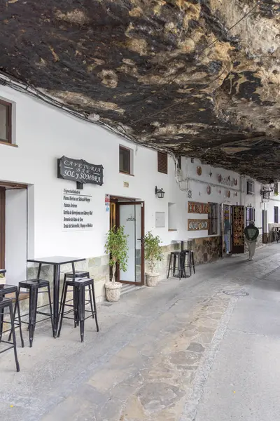Setenil de las Bodegas, İspanya, Endülüs - 2 Nisan 2025: Uçurumun üzerindeki eşsiz beyaz köy kayalara inşa edildi. Cuevas de la Sombra Caddesi 'ndeki dar dükkan ve restoranlar.