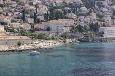 Dubrovnik, Hırvatistan - 27 Haziran 2023: Adriyatik Eski Liman Denizi 'nin ortaçağ kentini çevreleyen şehir surları ve körfezin yukarısında evlerle dolu bir tepe