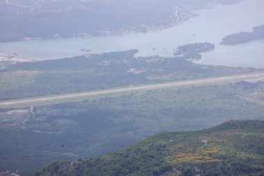 Adriyatik Denizi kıyısındaki Kotor Körfezi, Karadağ 'dan Tivat Havaalanı' nın havadan görünüşü. Ünlü Kotor Serpentine yolu ile ulaşılan dağın tepesindeki gözlem güvertesinden görüntüyü al