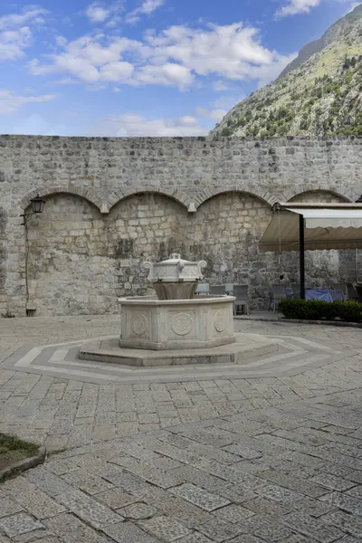 Kotor, Karadağ - 26 Haziran 2023: Taş dekoratif Su Fıskiyeli Eski Şehir Duvarları Tahta Meydanı manzarası
