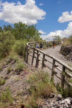 Mount Vesuvius, Naples, Italy - July 29, 2021: Tourists walking along the footpath to the top of Vesuvius volcano on a hot day. The path is made of sharp volcanic tuff