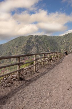 Mount Vesuvius, Naples, Italy - July 29, 2021: Tourists walking along the footpath to the top of Vesuvius volcano on a hot day. The path is made of sharp volcanic tuff