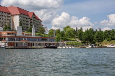 Mikolajki, Masuria, Polonya - 24 Haziran 2020: Lüks Golebiewski Oteli Mikolajskie Gölü manzaralı, ünlü tatil beldesi. Marina turist gemileri ve sahil şeridi için. Mikolajki 'ye Polonya' nın yelkencilik başkenti deniyor.