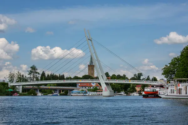 Mikolajki, Masurian Lake Land, Polonya - 24 Haziran 2020: Asma köprünün Mikolajskie Gölü manzarası, yat ve tekneler için yat limanı. Kutsal Üçlü Kilisesi