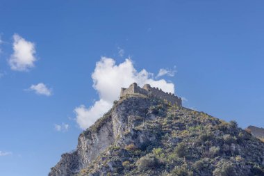 Castelmola, Sicilya, İtalya - 28 Nisan 2023: Mola Kalesi harabeleri ile kayalık dağın tepesi, küçük bir çayırın üzerindeki tepenin üzerindeki eski Norman tahkimatlarının bir parçası. Küçük köy son zamanlarda popüler bir turizm beldesi oldu.